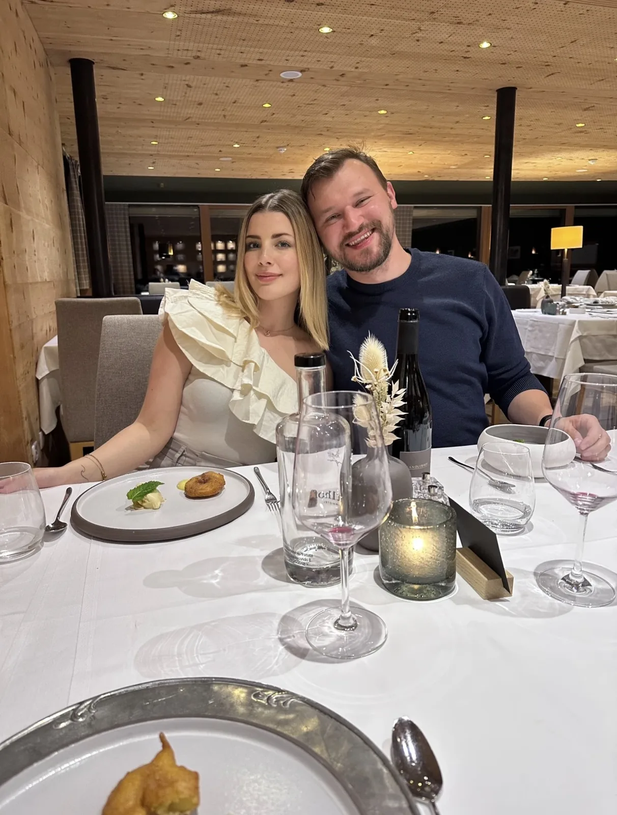 Velena and Dragos at dinner at the Leitlhof in San Candido, a plated dessert and a bottle of local red on the table